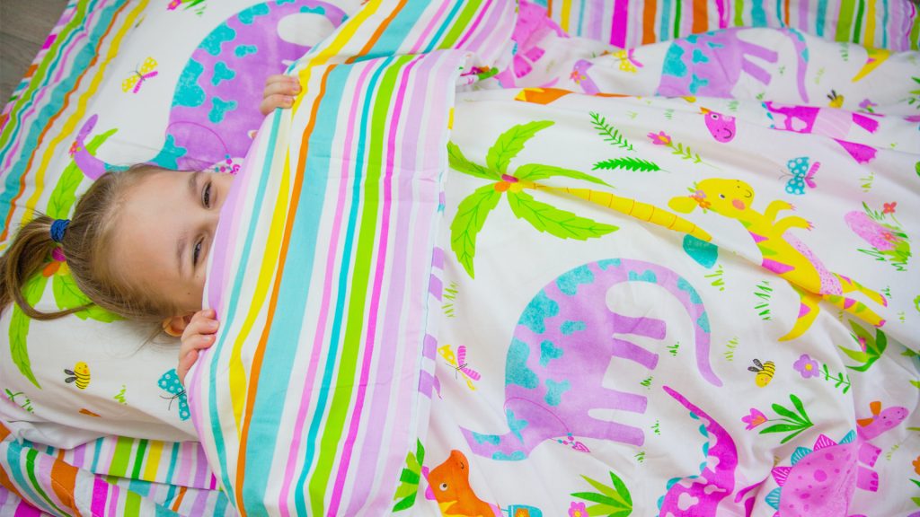 Girl sleeping in dinosaur kids bedding